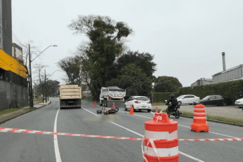Motociclista atravessa cruzamento, bate em caminhão, para embaixo do rodado e morre atropelado em Curitiba